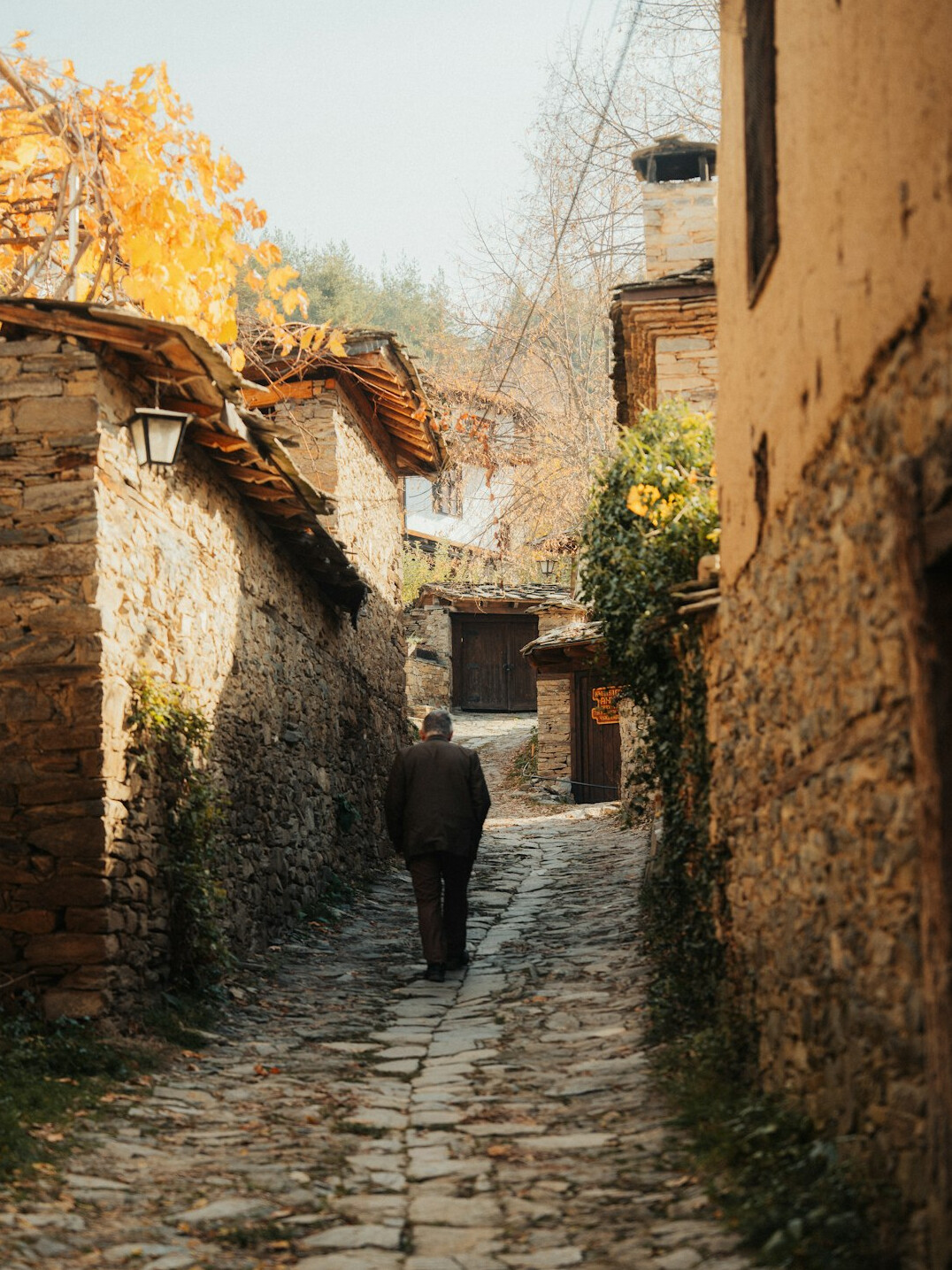 Photographer walking through a quiet Polish village street with a camera
